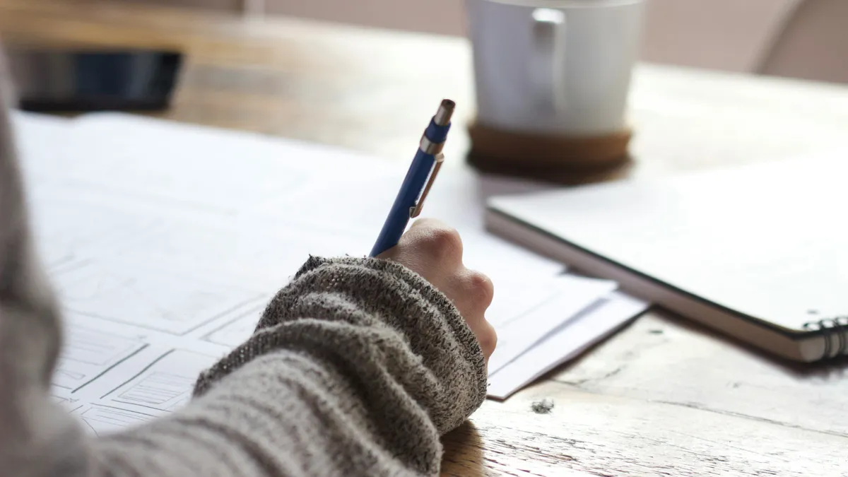 Persona escribiendo sobre papeles en un escritorio